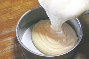 型の側面にバターをしっかり塗り、底にオーブンシートを敷く。（5）の生地を流し入れる。