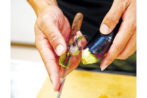 ナスのヘタは切り落とさず、ヘタ周りの皮だけを包丁で丁寧に剝ぎ取ります。