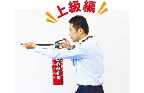 消火器のホースを顔の手前まで持ち上げて構えると、炎の熱から顔を守ることができます
