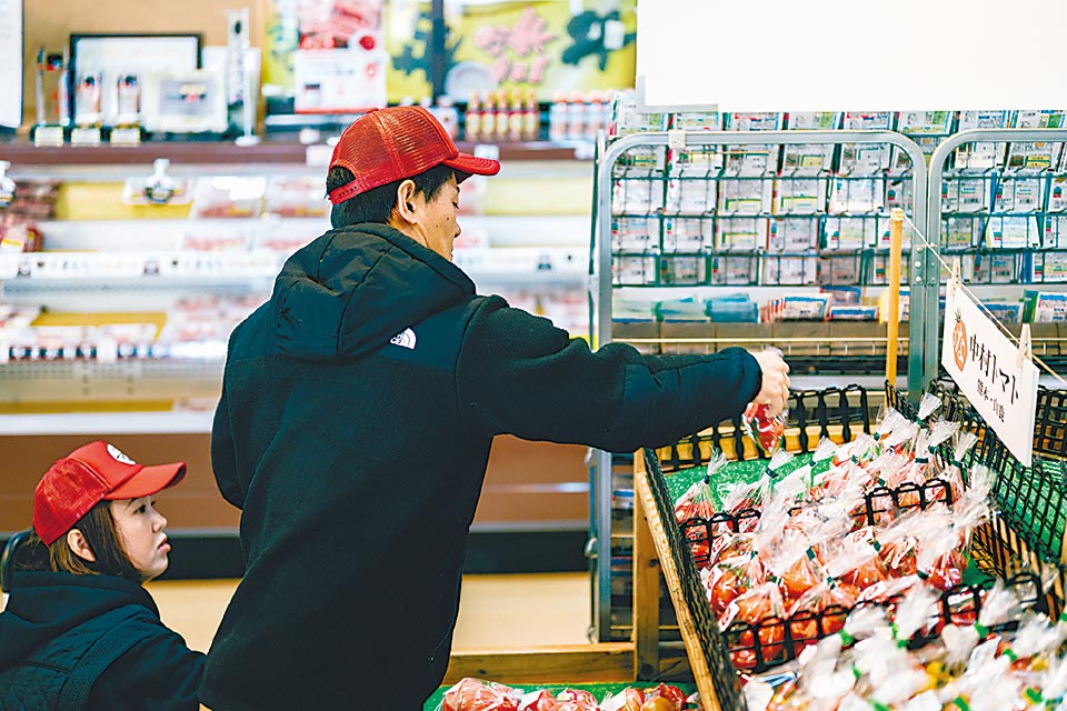夢大地館の売り場にミニトマトを並べる中村さん夫妻。「新鮮なミニトマトは格別のおいしさ。ぜひ食べてみてください」と話します