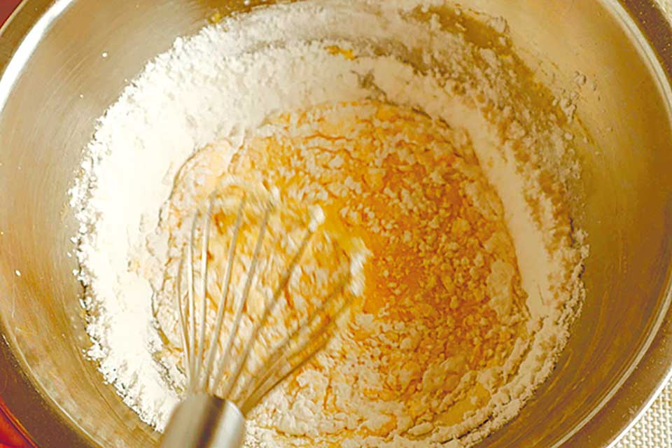 米粉とベーキングパウダーを加え、よく混ぜ合わせる。オーブンを170℃に予熱する。