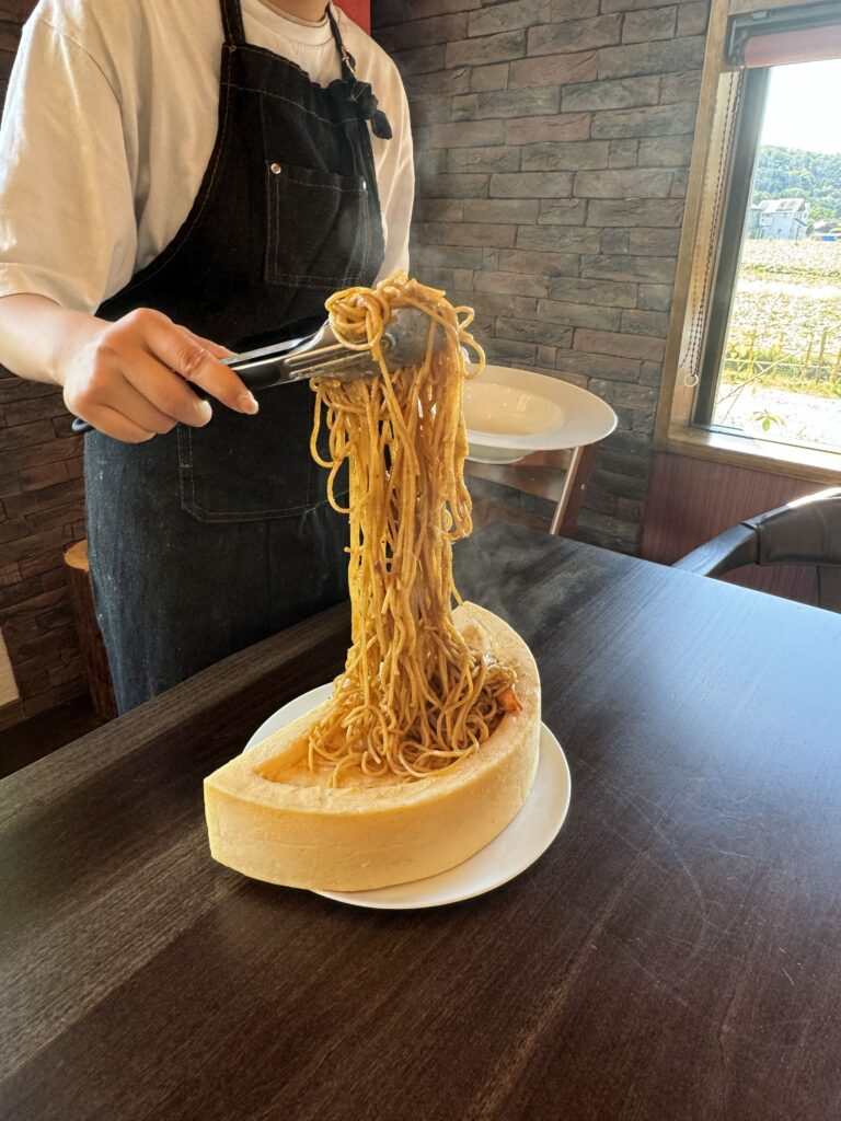 ラクレットチーズにのったパスタをお皿に移す様子