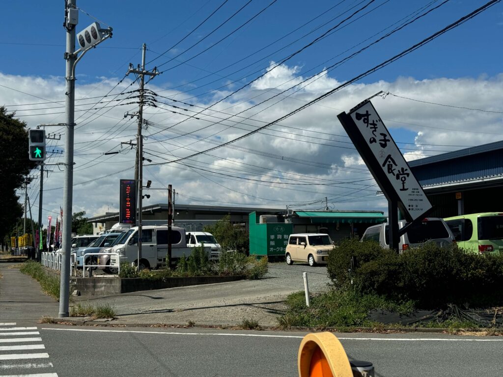 車屋さんの電子看板の手前に「すぎの子食堂」と書かれた白い看板が右手に見えます。