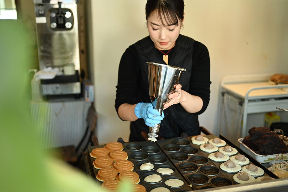 妙見まんじゅうを焼く店主の長谷川さん。まんじゅうの表面には妙見宮の二つの神紋をデザインした文様が