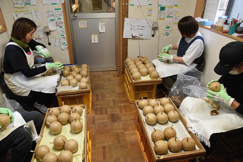 花火玉の仕上げ作業でクラフト紙を巻き付けるスタッフさんたち
