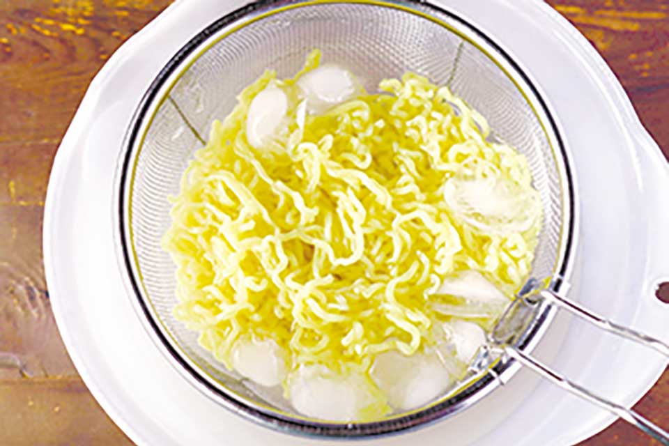 沸騰した湯で中華麺をゆでる。ザルに取り流水で洗って氷水で締め、手でギュッと押さえてしっかりと水気を絞る。