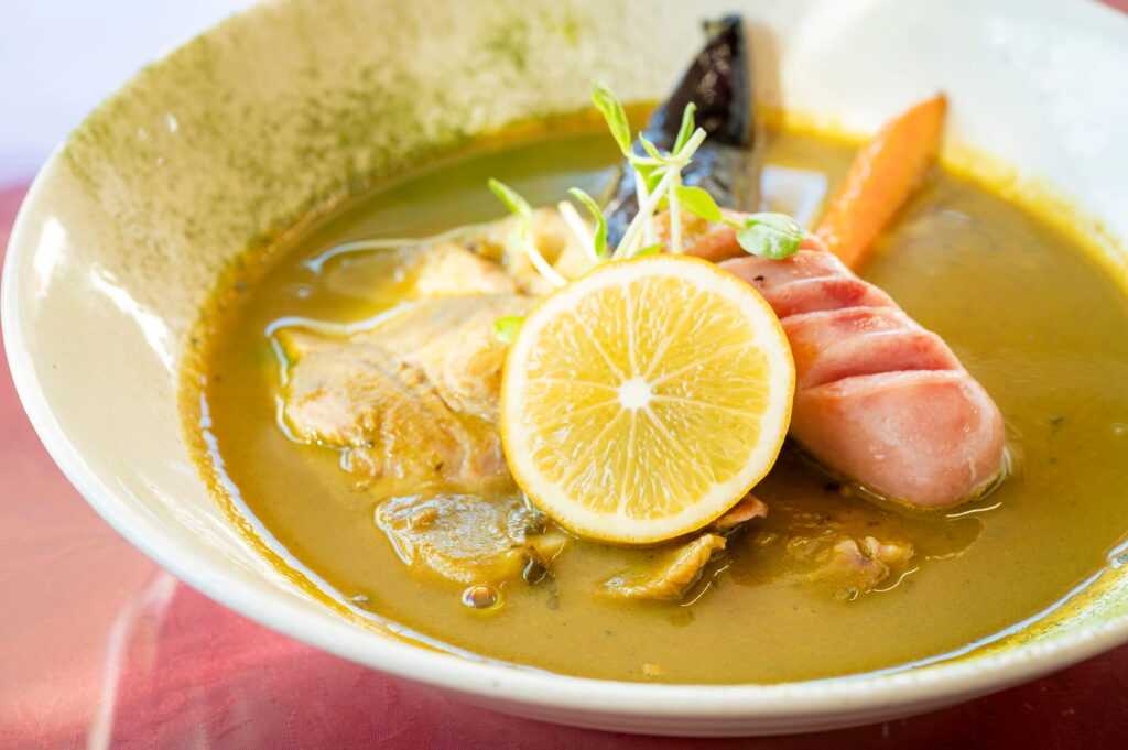 「豚肉とフランクのグリーンスープカリー」（1370円）。タイのグリーンカレーではなく、抹茶の風味を生かした同店のオリジナルカレー