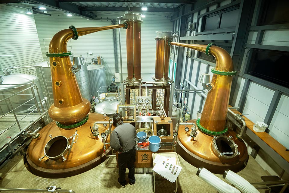 ショップ営業日には自由見学通路から純銅製の蒸留器を見ることができます。有料ガイドツアーでは樽熟成庫（右）の見学も