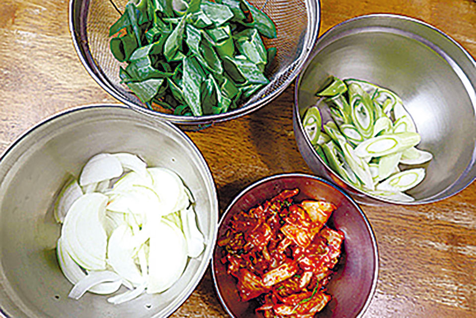 タマネギは薄切り、長ネギは白い部分と葉の部分に分け、斜め切りにする。キムチは食べやすい大きさに切る。