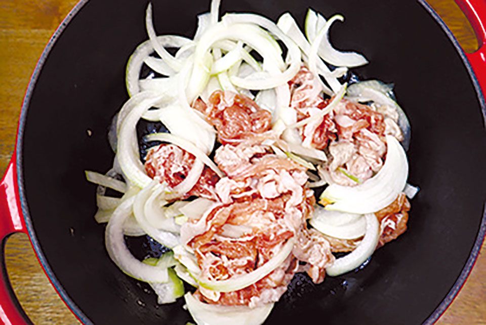 鍋にごま油を熱し、豚肉とタマネギを炒める。肉の色が変わったらキムチを加えて炒める。