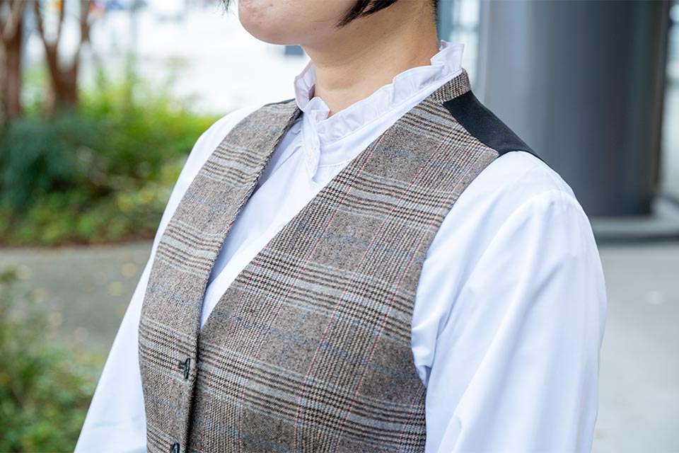 ハンサムな表情のチェック柄ベストと甘い雰囲気の襟元のフリルできれいめマニッシュに。