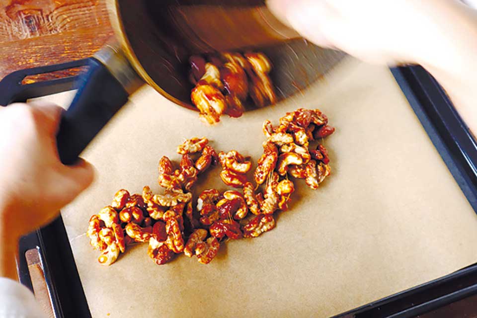 （2）にバター、（1）のナッツをすぐに加えてよく絡める。再度弱火にかけ、混ぜながら30秒ほど火を通したら、クッキングシートの上に広げて冷ます。