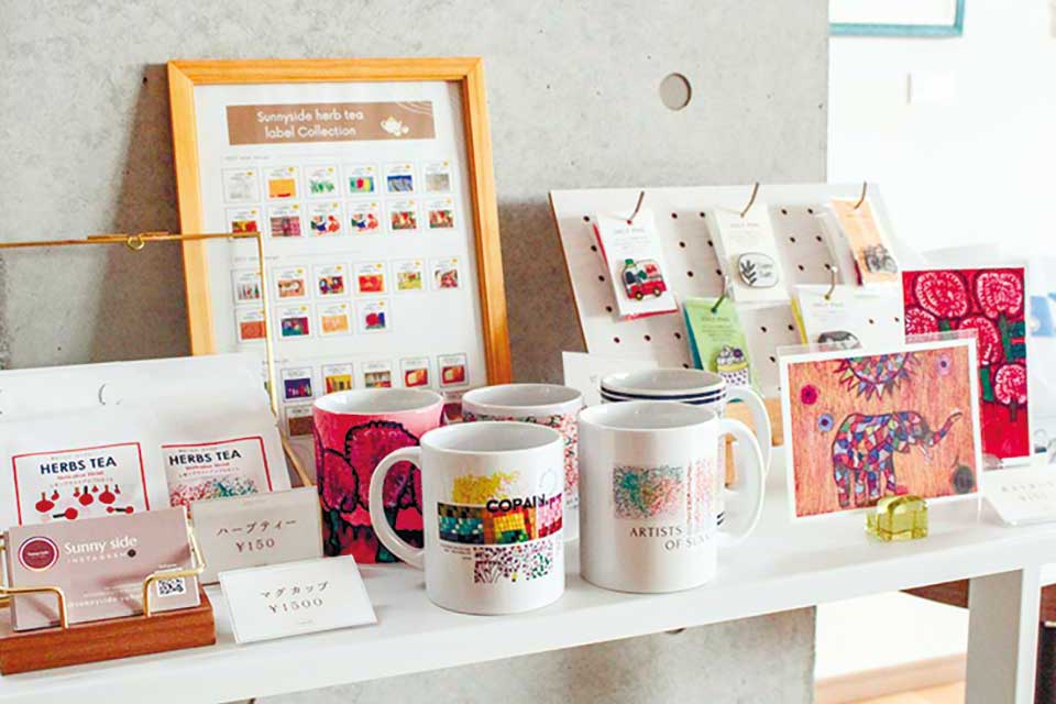 絵が使用されたハーブティー(150円)のパッケージやマグカップ(1500円)
