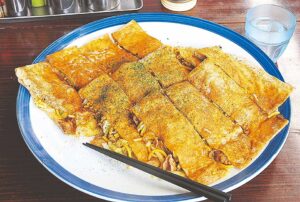 熊本を代表するB級グルメ「ちょぼ焼」350円～。肉、イカ、エビ、野菜、麺、卵全部を入れても900円。トッピングやスパイスで多彩な味わいを楽しんで