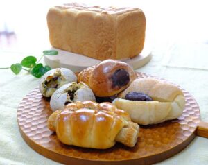 時計回りに、生食パン（2斤サイズ、800円）、チョココロネ、塩あんバター（各180円）、人気のちくわパン（190円）、豆もちパン（2個入り、190円）