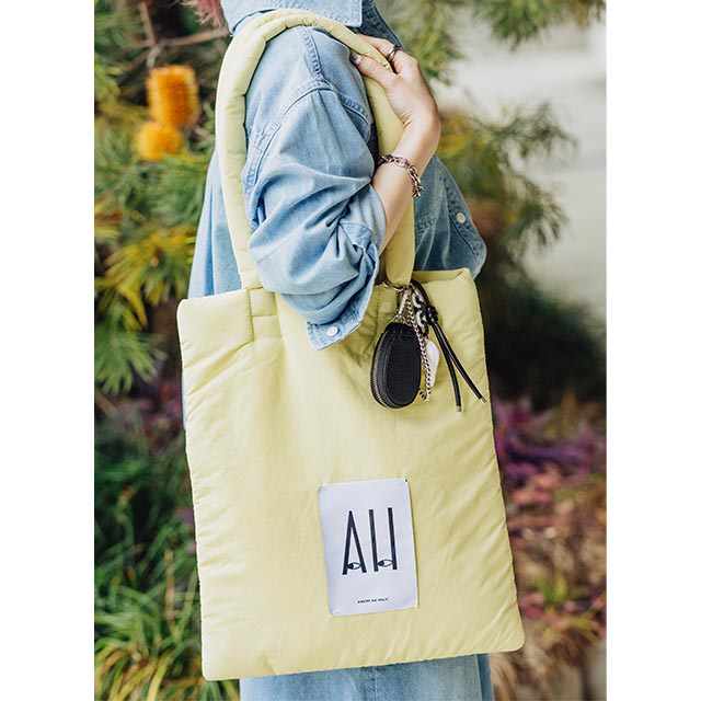 レモンイエローのバッグを差し色としてプラス。黒ベースのバッグチャームを付けると、ほかの小物と一体感が生まれます。