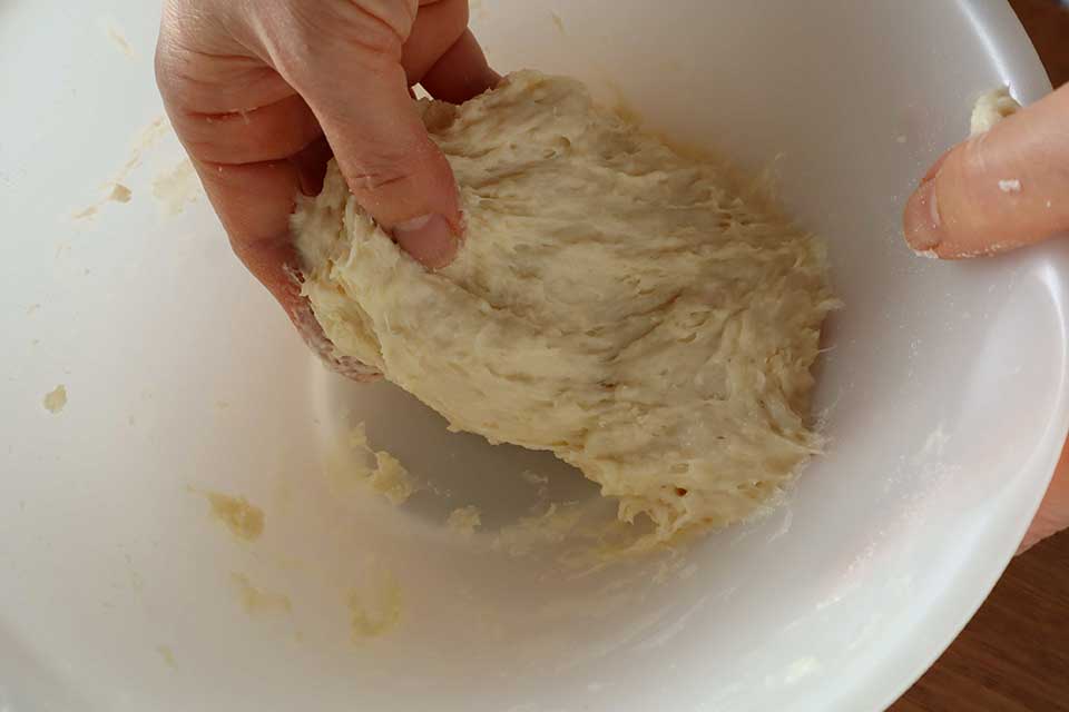 砂糖、塩、湯、サラダ油を混ぜ合わせ、（1）に加えて手でよく混ぜる。最初はベタつくが、ボウルの中でたたきつけるようにしながらこね続ける。だんだんと生地がまとまり、表面がなめらかになってきたらOK。ラップをかけて30分ほど休ませる。